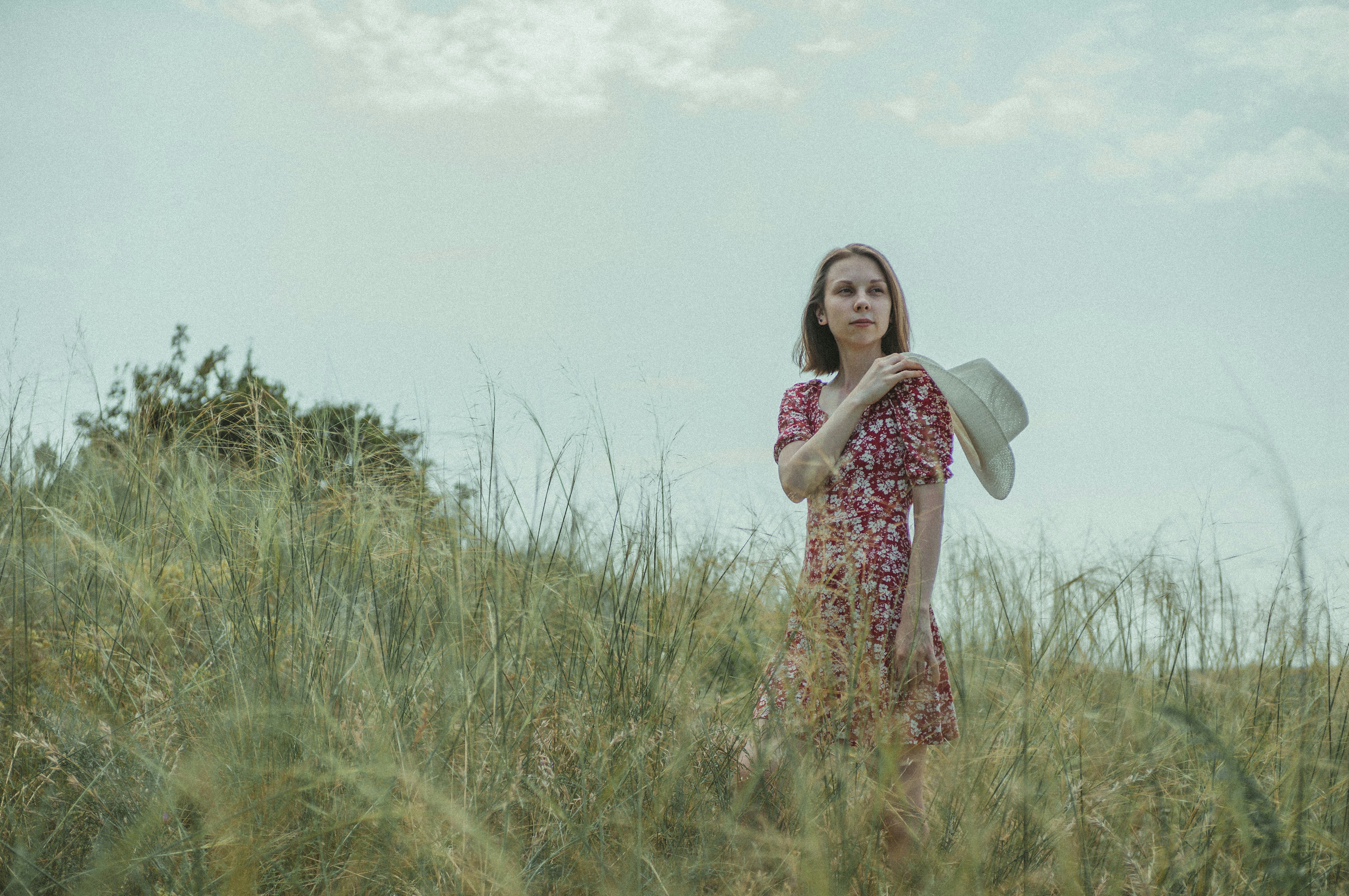 woman in purple and white floral dress standing on green grass field during daytime